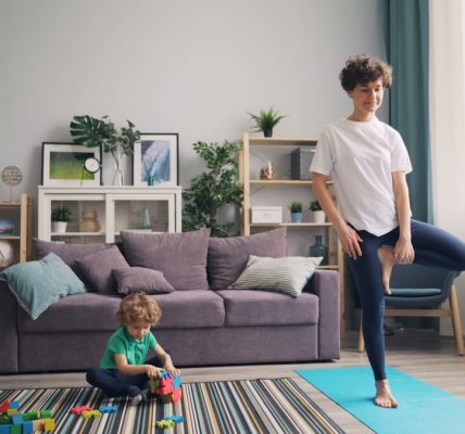 a woman standing in a living room next to a child